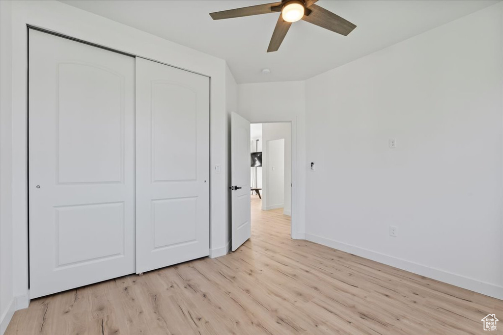 Unfurnished bedroom with light wood finished floors, baseboards, a closet, and a ceiling fan