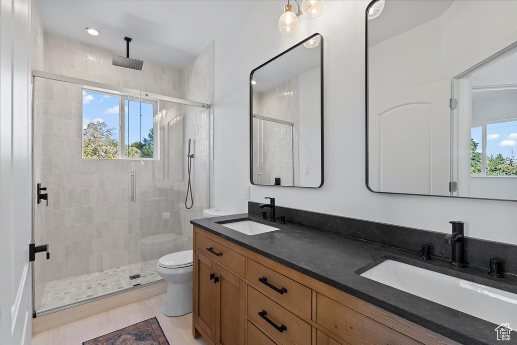 Bathroom with double vanity, toilet, a stall shower, and a sink