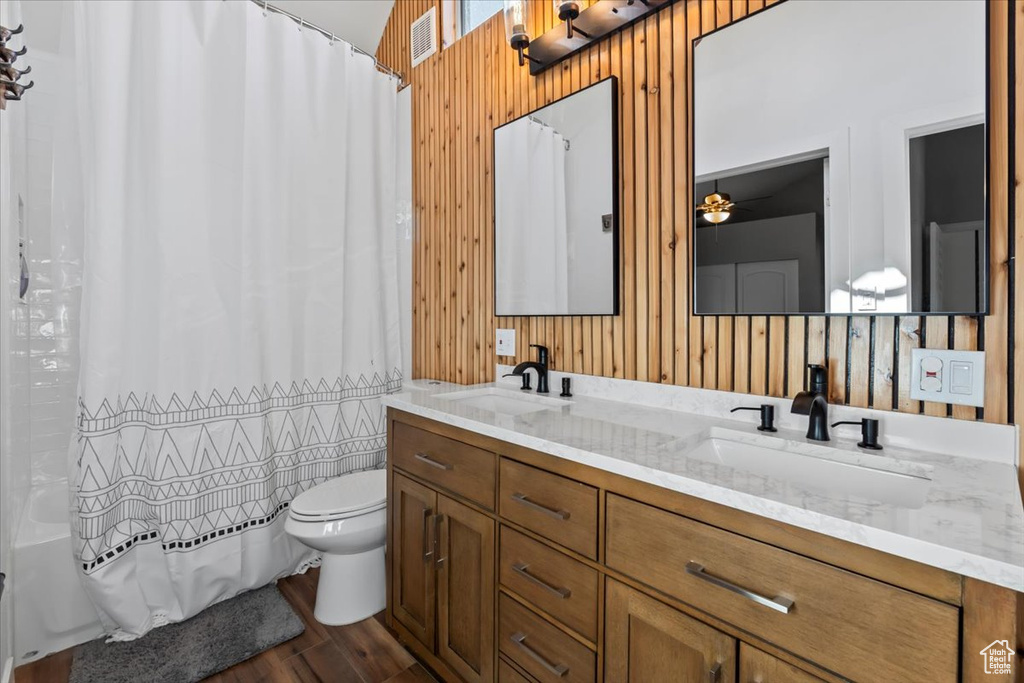 Bathroom featuring double vanity, toilet, shower / tub combo, and a sink