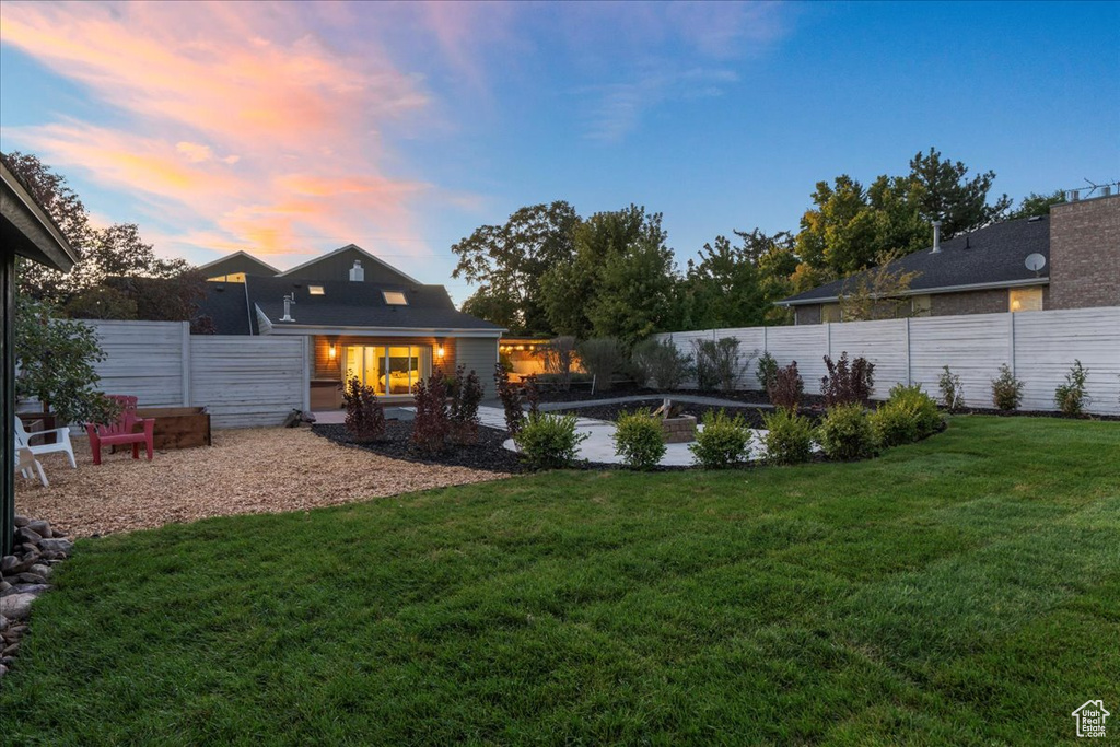 Yard at dusk featuring a patio and a fenced backyard
