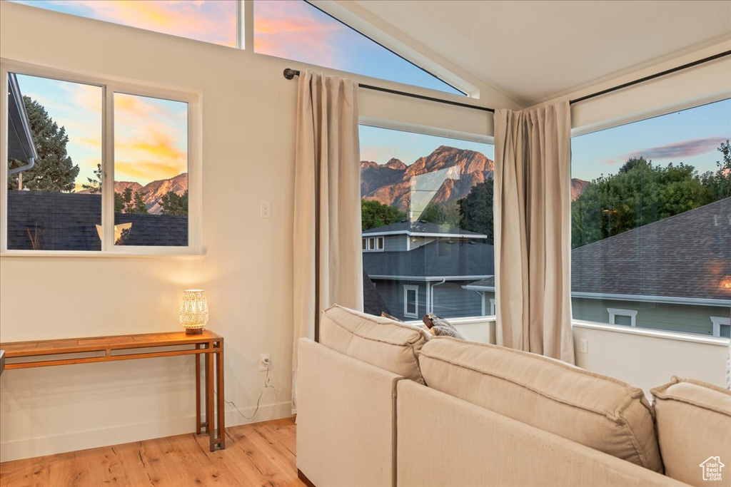 Living room featuring lofted ceiling, wood finished floors, a mountain view, and baseboards