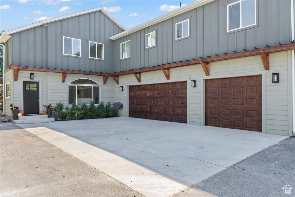 View of property featuring board and batten siding, concrete driveway, and a garage