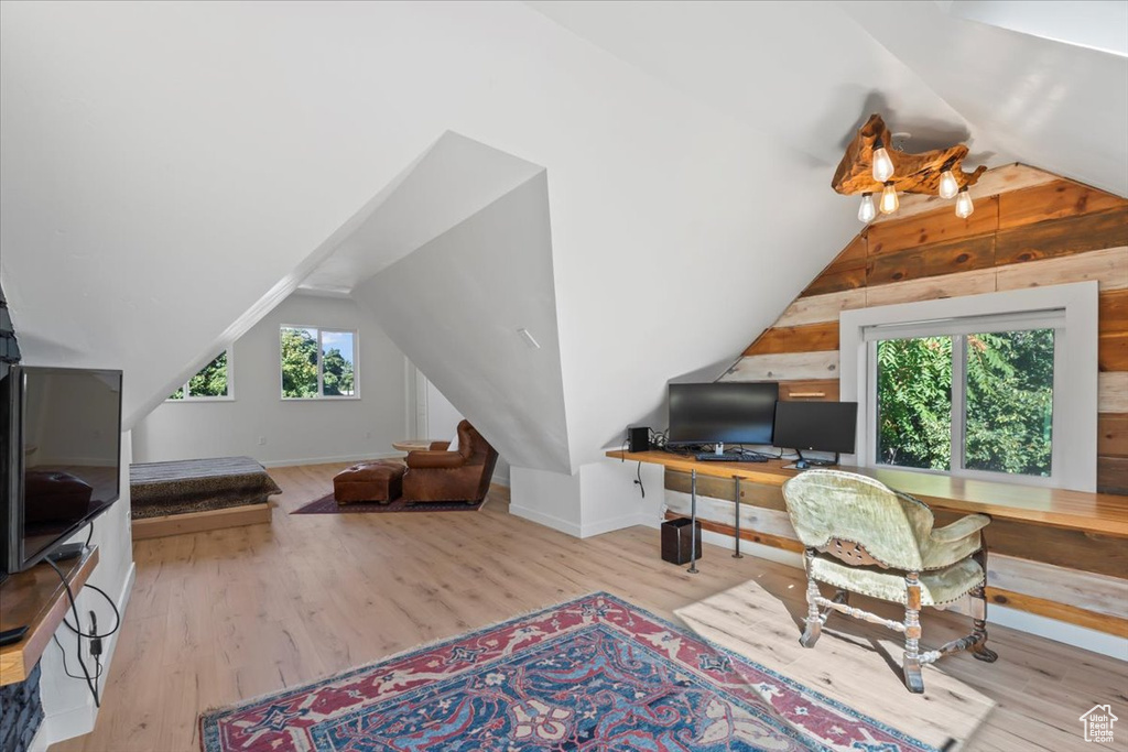 Interior space with vaulted ceiling, baseboards, and wood finished floors