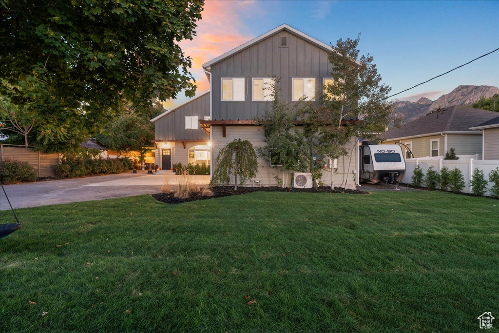 View of front of property with fence, board and batten siding, driveway, and a lawn
