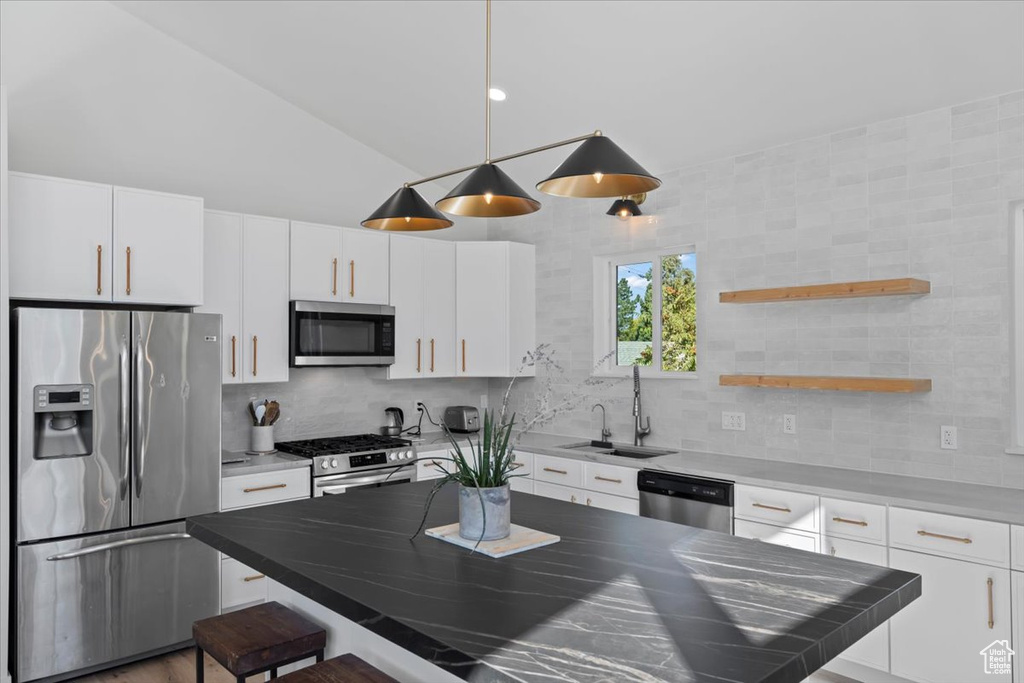 Kitchen featuring a sink, stainless steel appliances, a breakfast bar, and white cabinetry