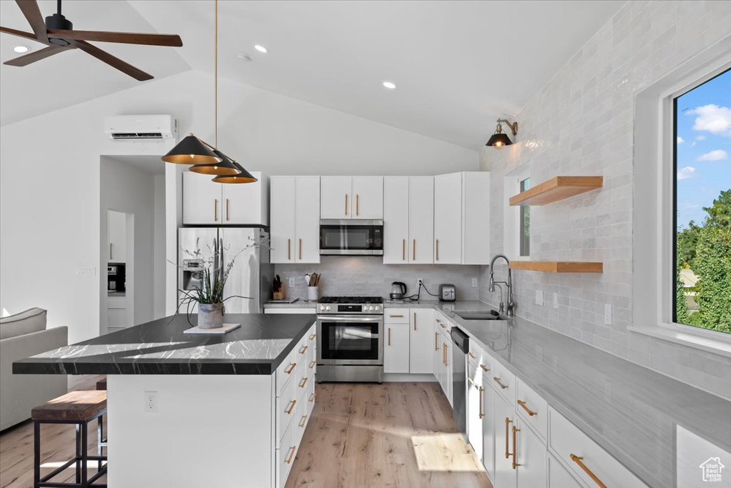 Kitchen featuring a sink, a wall mounted air conditioner, a kitchen bar, stainless steel appliances, and open shelves
