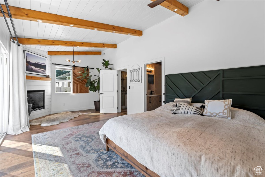Bedroom with a fireplace, wood ceiling, wood finished floors, and vaulted ceiling with beams