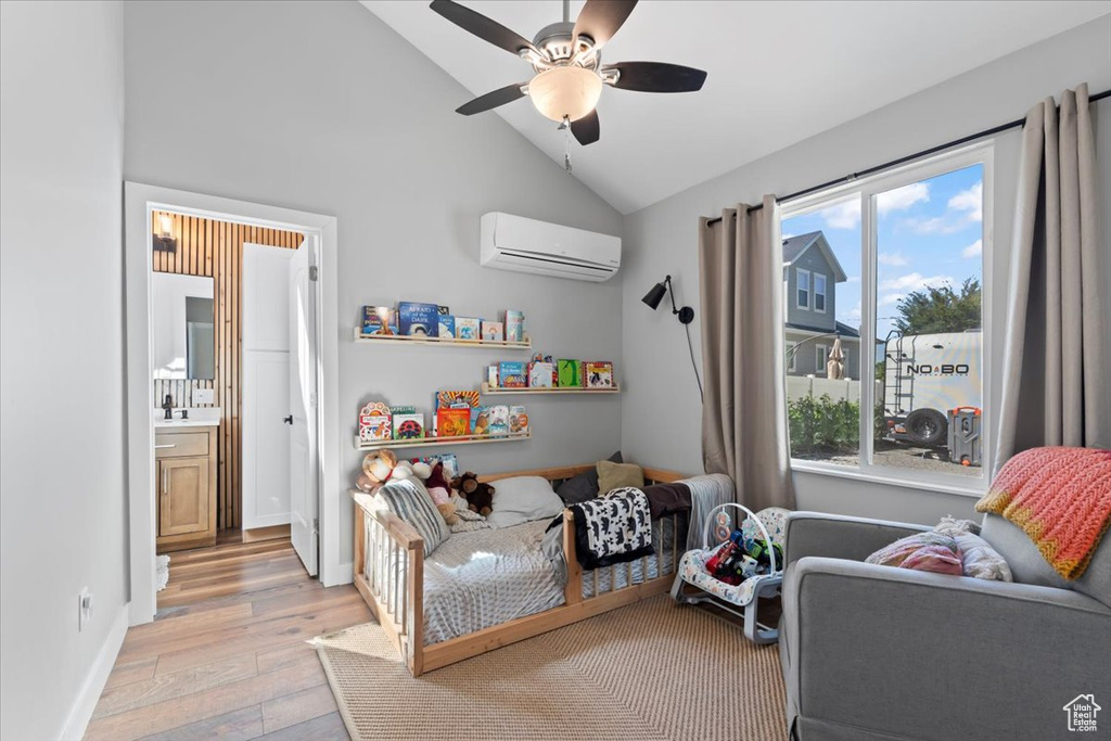 Bedroom with baseboards, ceiling fan, lofted ceiling, a wall unit AC, and light wood-style flooring