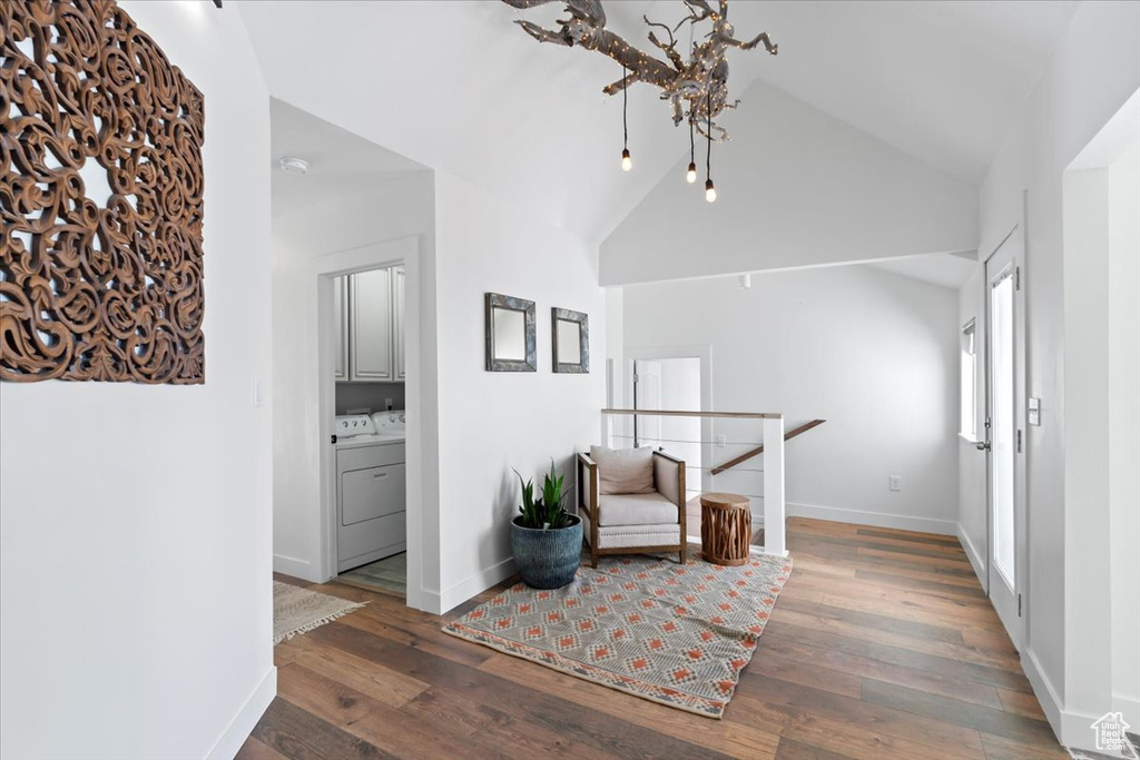 Sitting room featuring washing machine and dryer, baseboards, wood-type flooring, and high vaulted ceiling