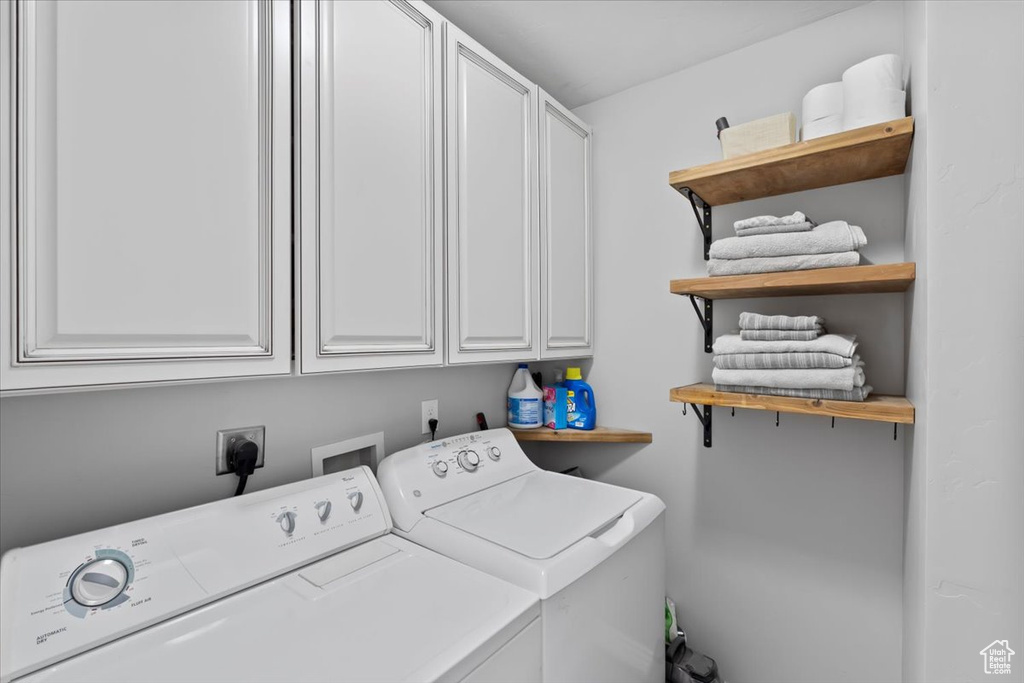 Clothes washing area featuring cabinet space and separate washer and dryer