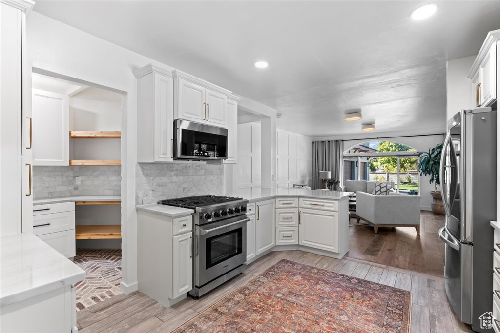 Kitchen with open floor plan, appliances with stainless steel finishes, and white cabinetry