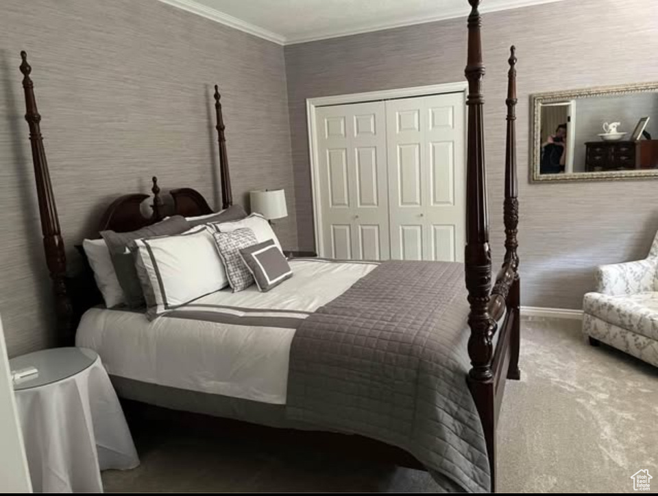 Carpeted bedroom featuring baseboards, a closet, and ornamental molding