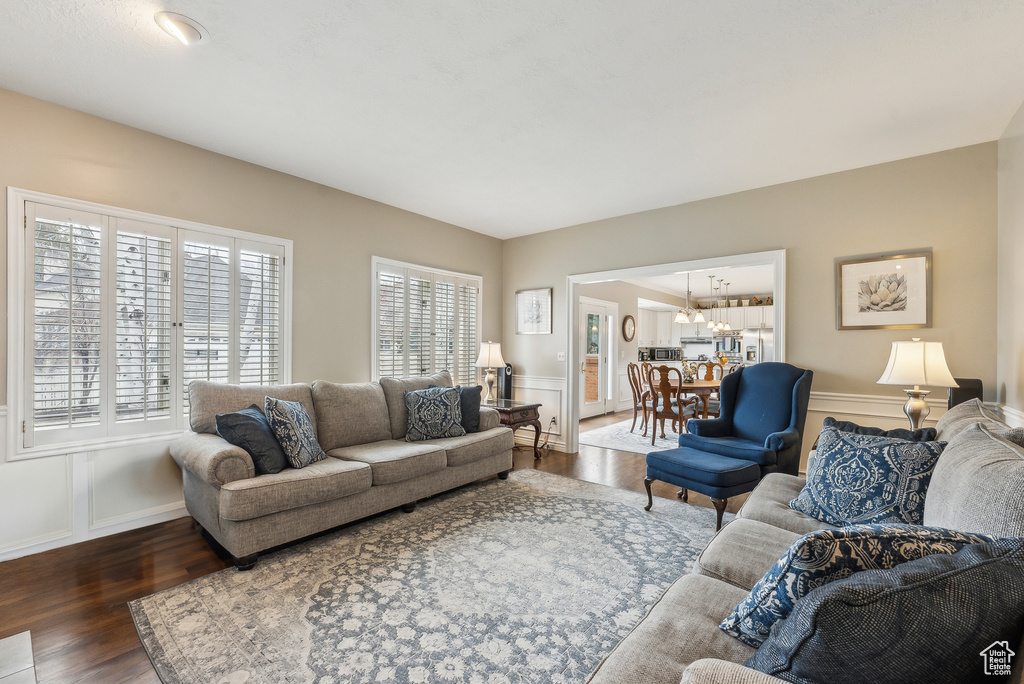 Living area with an inviting chandelier, plenty of natural light, and wood finished floors