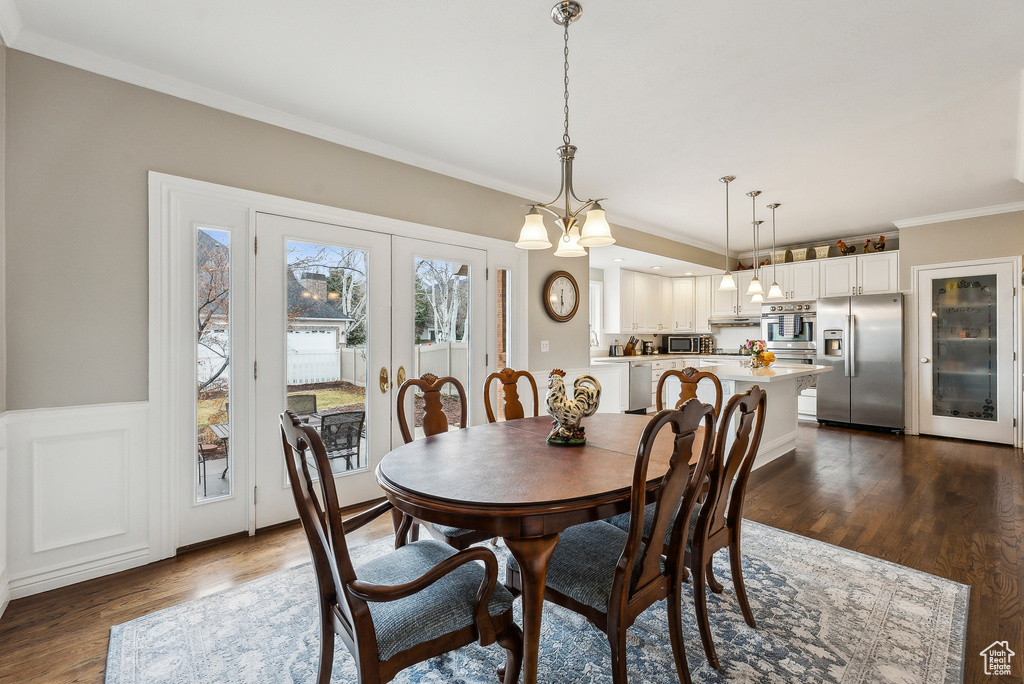 Dining space featuring french doors, a wainscoted wall, dark wood-style flooring, and crown molding