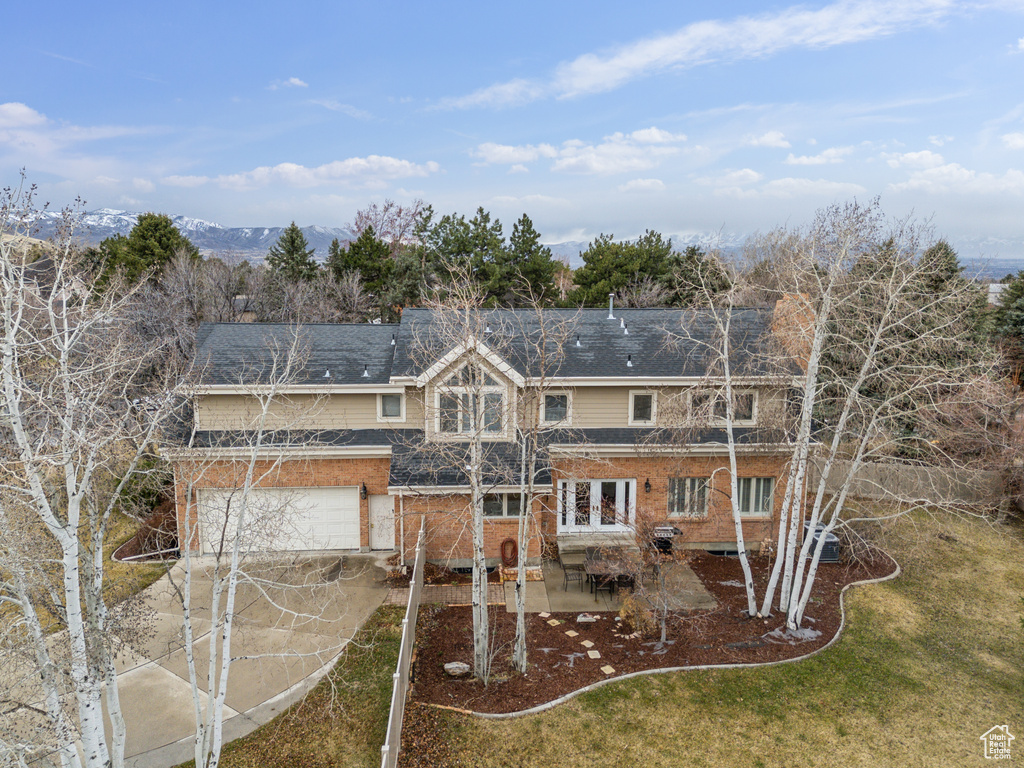 Exterior space with brick siding, driveway, a yard, a patio area, and an attached garage