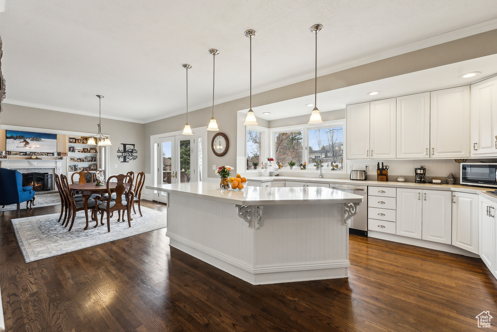 Kitchen featuring stainless steel appliances, a kitchen island, dark wood-style flooring, and light countertops