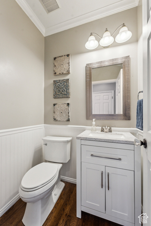 Bathroom with wood finished floors, visible vents, a wainscoted wall, ornamental molding, and toilet