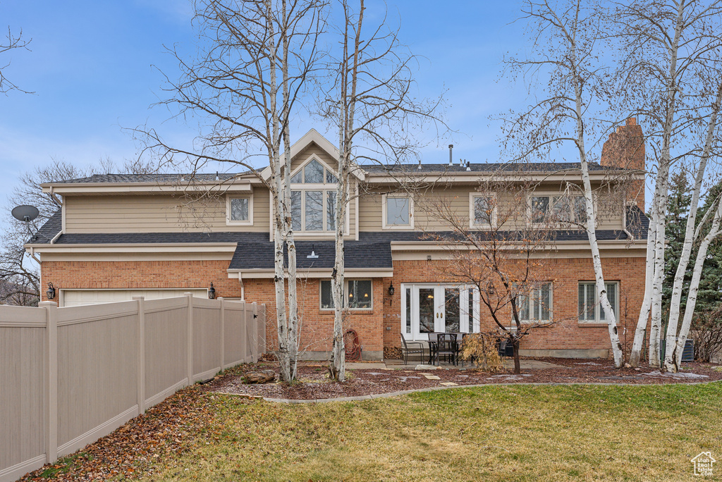 Back of house with french doors, brick siding, a yard, and fence