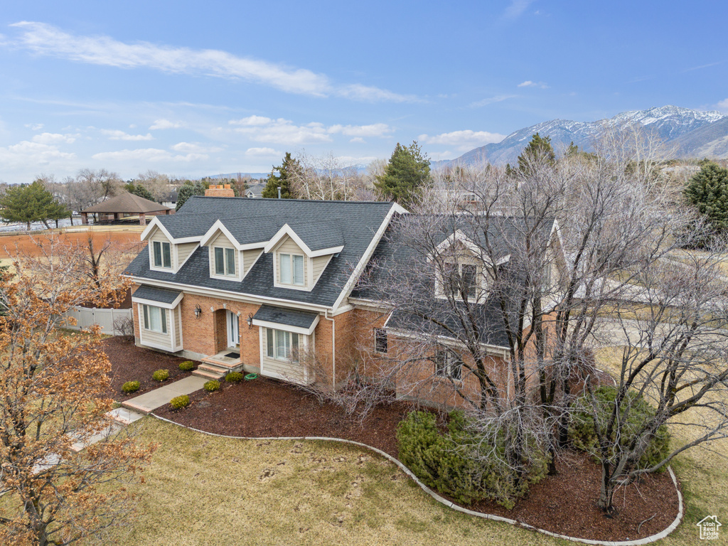 View of front of house with a mountain view, fence, brick siding, and a shingled roof