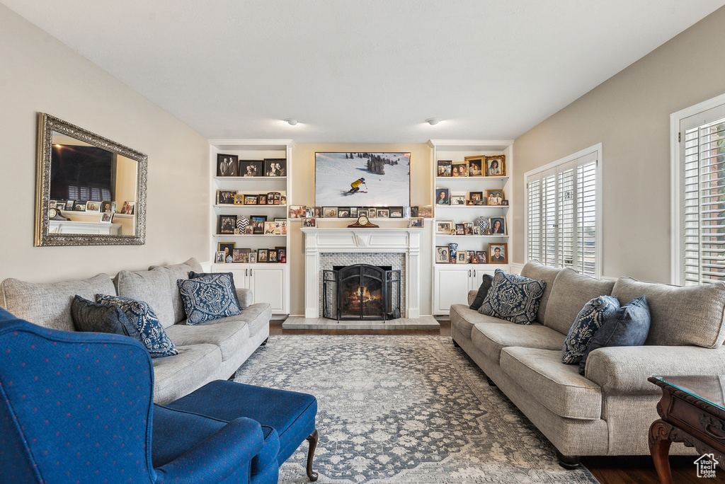 Living room featuring wood finished floors, built in features, and a fireplace