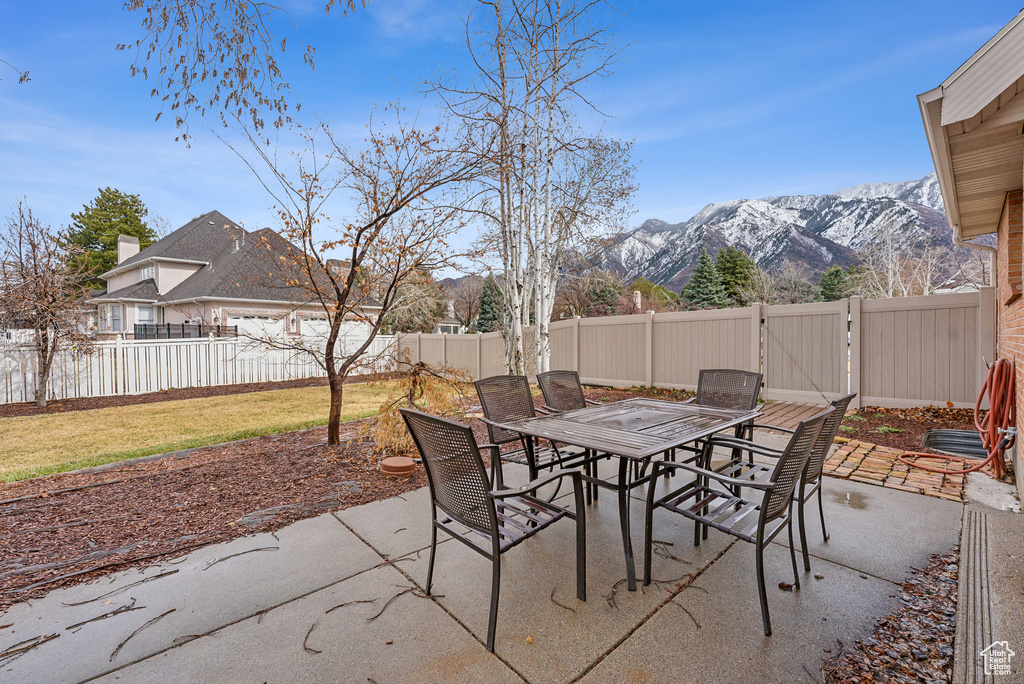 View of patio with outdoor dining space, a mountain view, and a fenced backyard