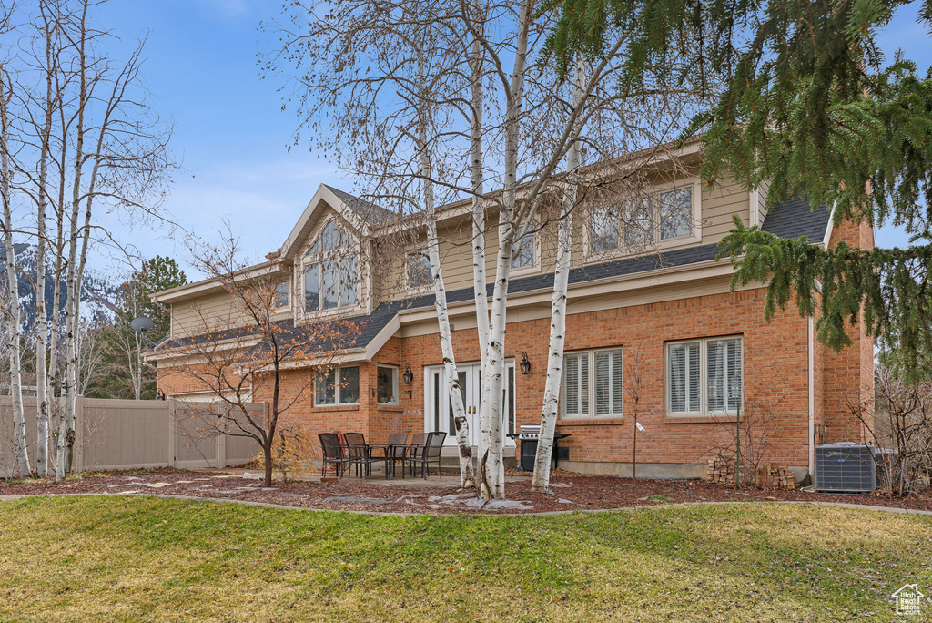 Rear view of house featuring a yard, brick siding, and fence