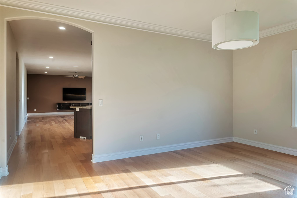 Unfurnished room with wood finished floors, recessed lighting, arched walkways, ornamental molding, and baseboards