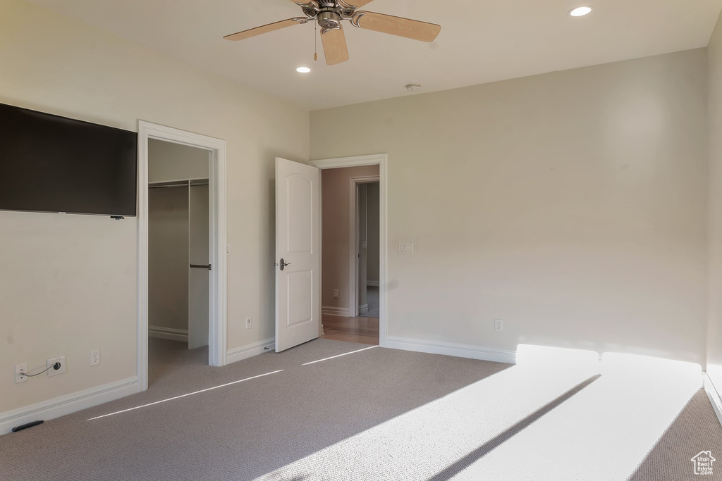 Unfurnished bedroom with carpet floors, recessed lighting, baseboards, a walk in closet, and a ceiling fan