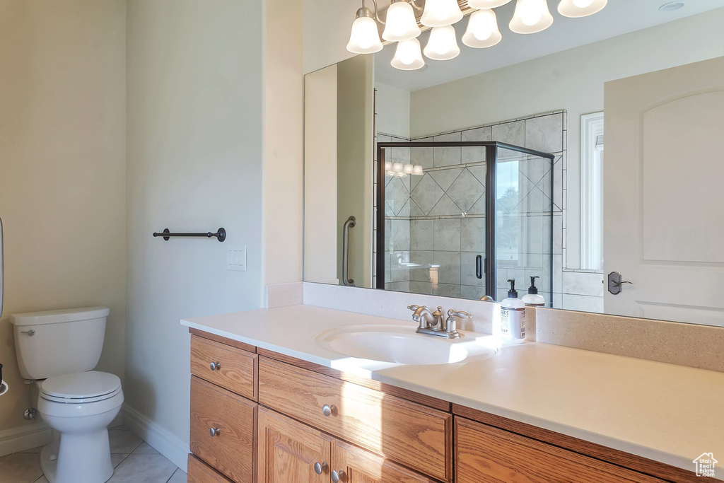 Bathroom featuring vanity, toilet, a stall shower, tile patterned flooring, and baseboards