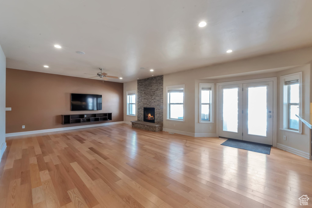 Unfurnished living room featuring light wood-style flooring, a stone fireplace, recessed lighting, a ceiling fan, and baseboards