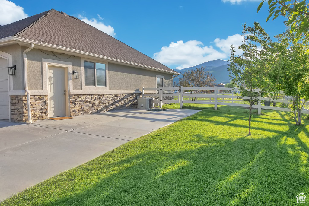 View of home\'s exterior with stucco siding, a mountain view, stone siding, and a shingled roof