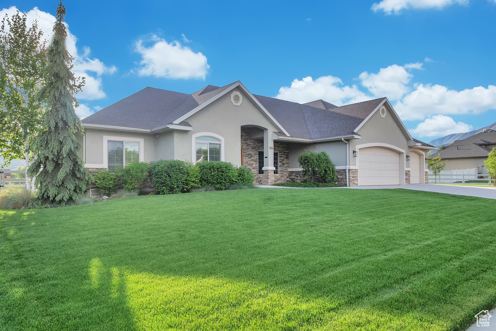 View of front of property featuring stucco siding, a front lawn, and stone siding