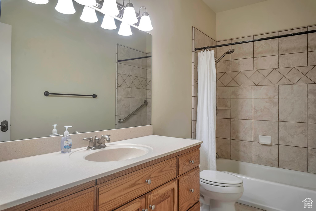 Bathroom with vanity, shower / bathtub combination with curtain, toilet, and a chandelier