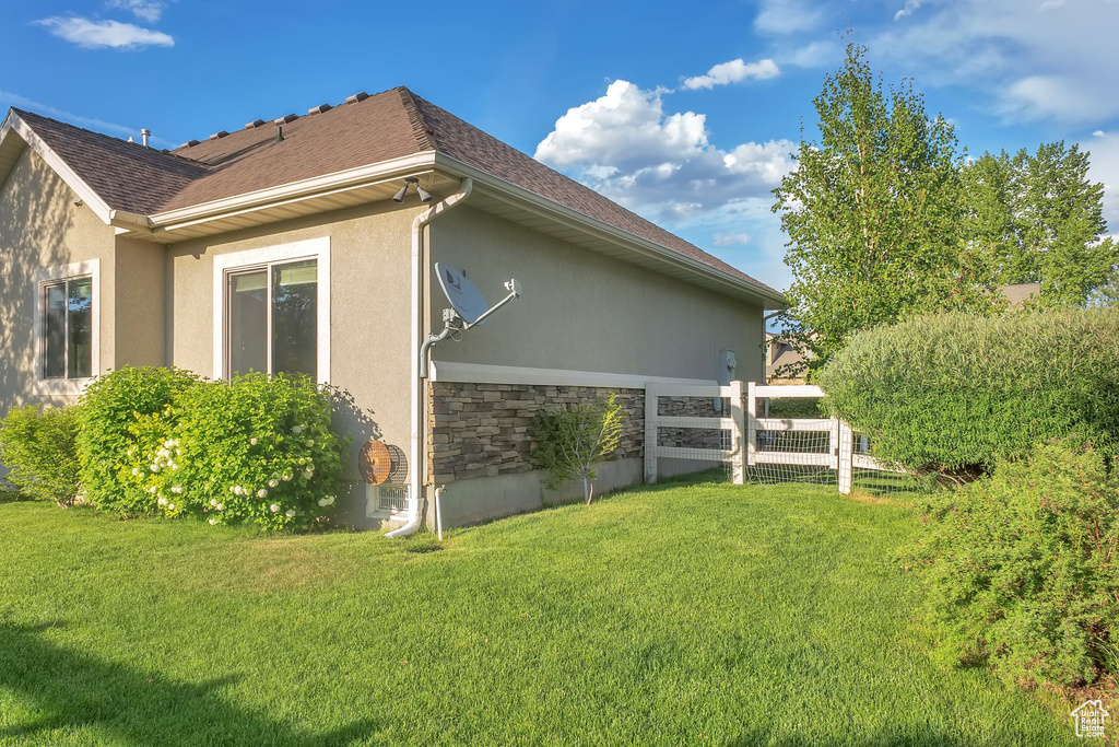 View of side of property featuring stucco siding, stone siding, and a shingled roof