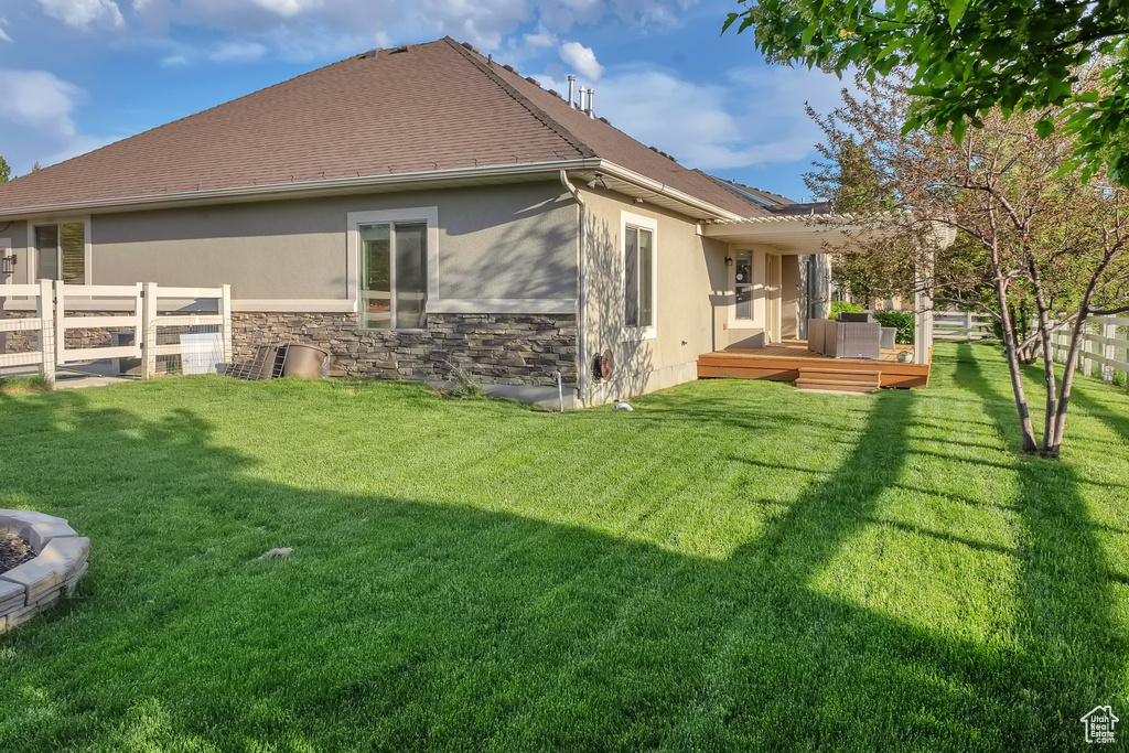 Rear view of property with stucco siding, a deck, and stone siding