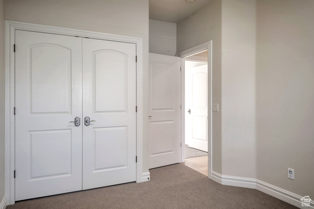 Unfurnished bedroom with carpet flooring, a closet, and baseboards