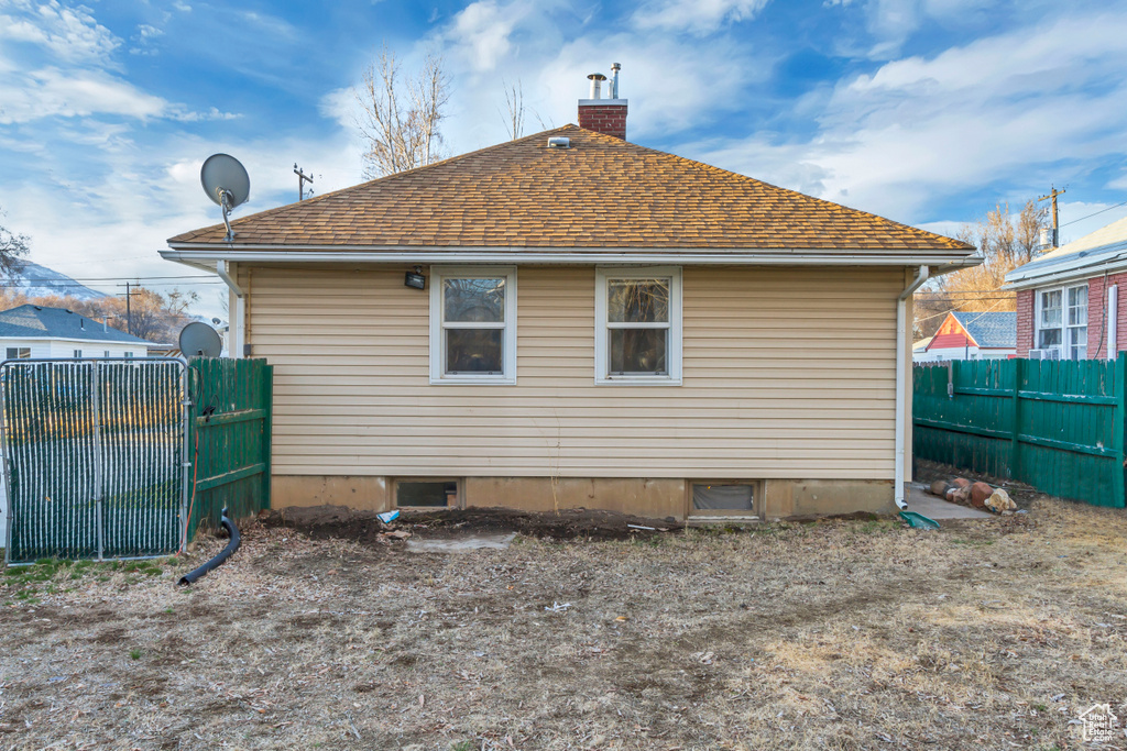 Back of property with a shingled roof, fence, and a chimney