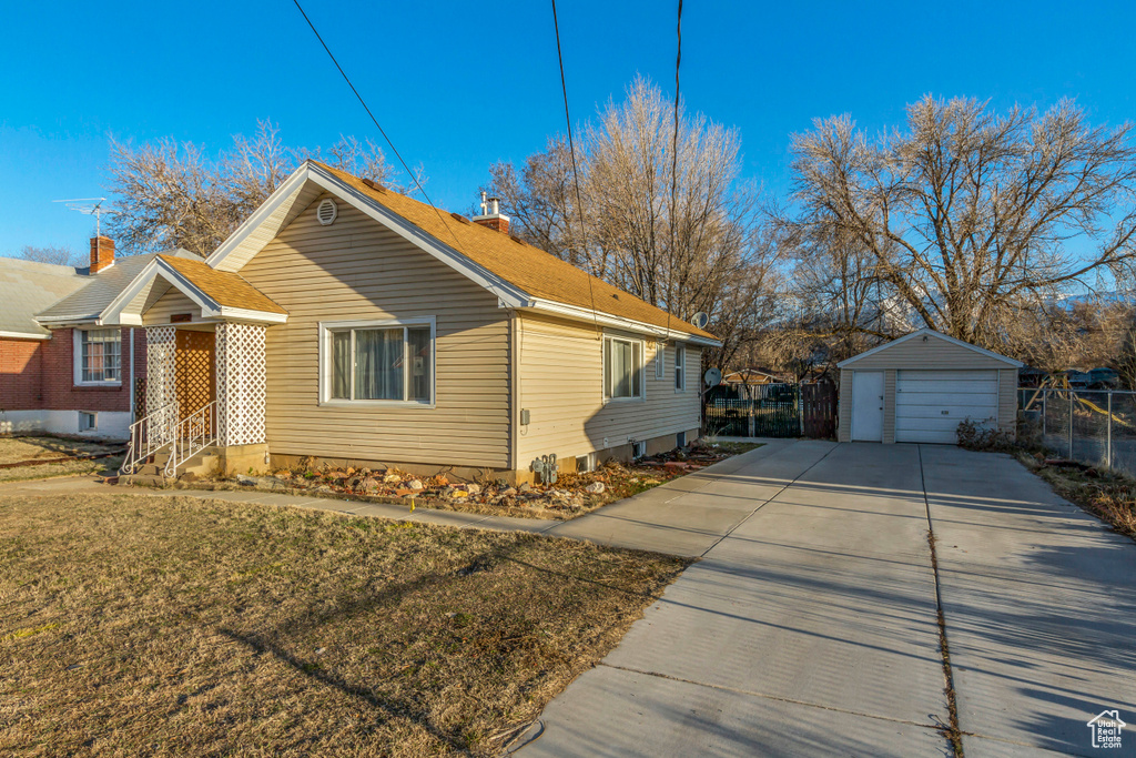 View of property exterior featuring an outbuilding, a yard, fence, and a garage