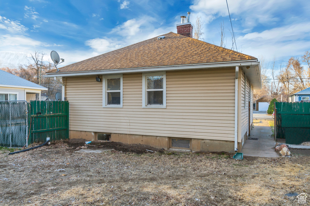Rear view of property with fence, roof with shingles, and a chimney