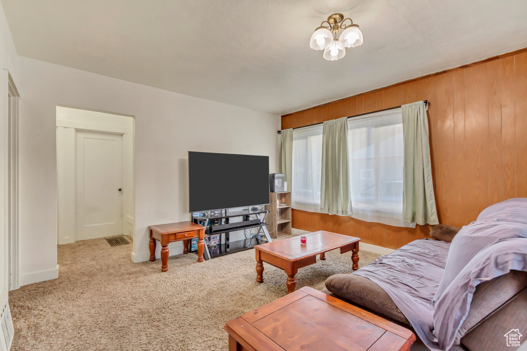 Living room with wooden walls, an inviting chandelier, and carpet