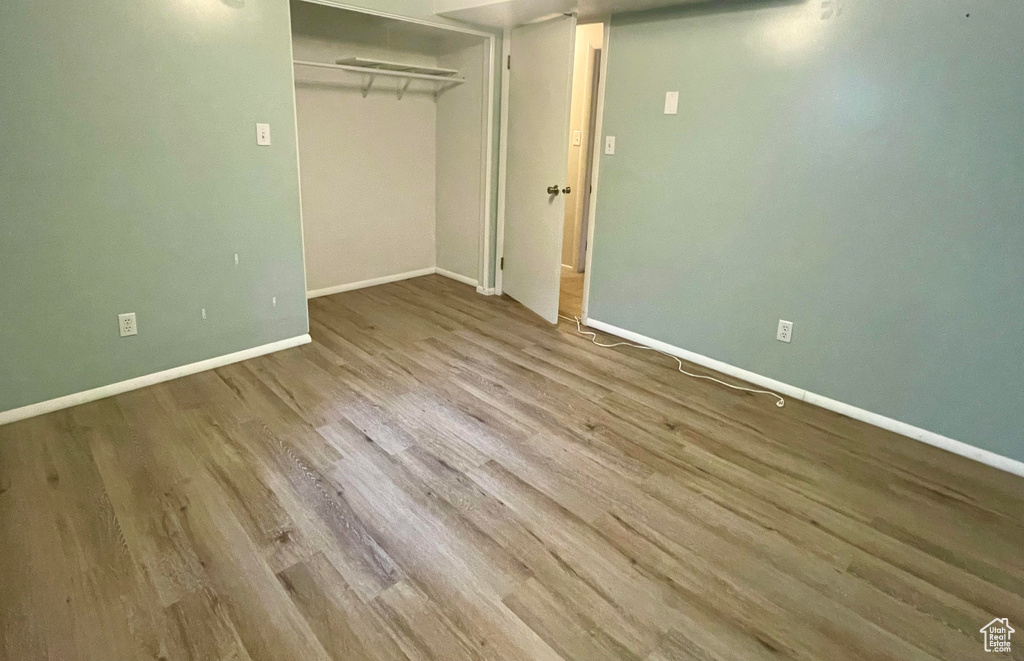 Unfurnished bedroom with wood finished floors, baseboards, and a closet