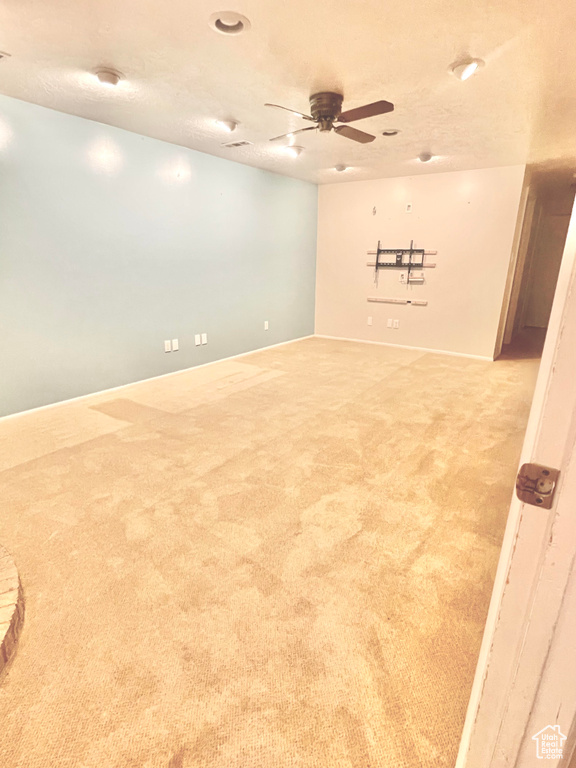 Carpeted empty room featuring a textured ceiling and ceiling fan