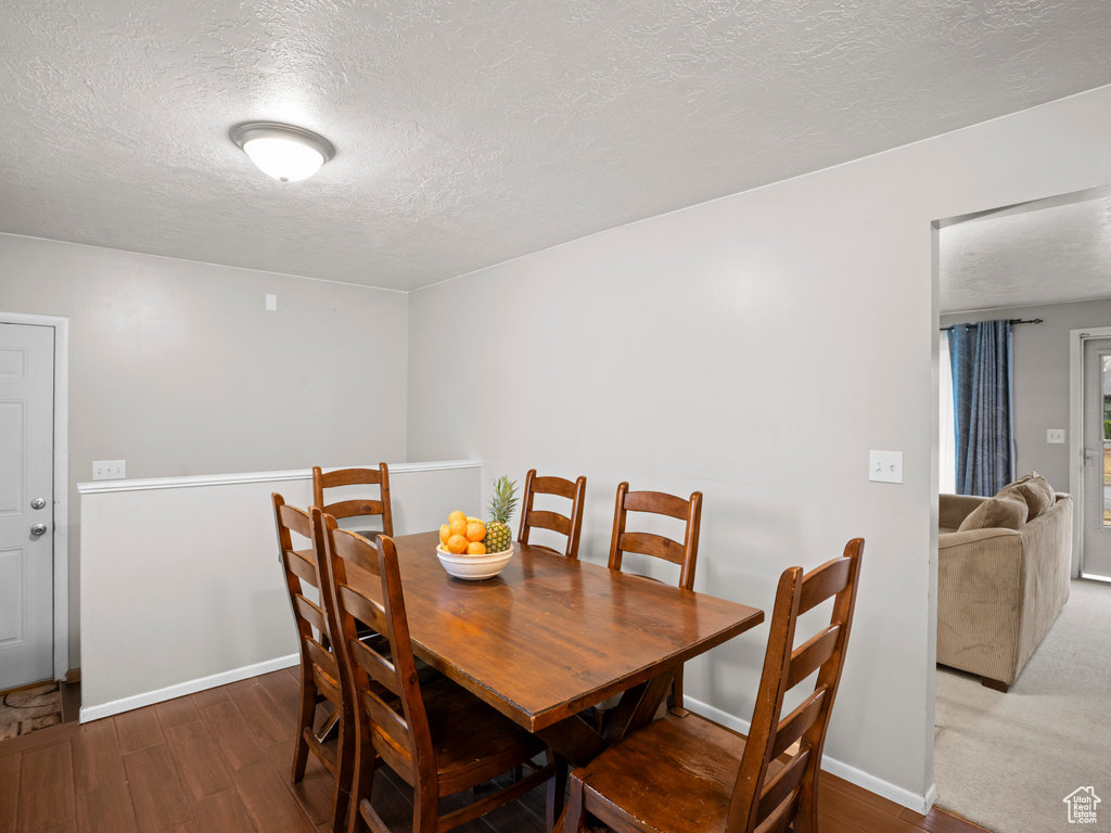Dining area with baseboards, a textured ceiling, and wood finished floors