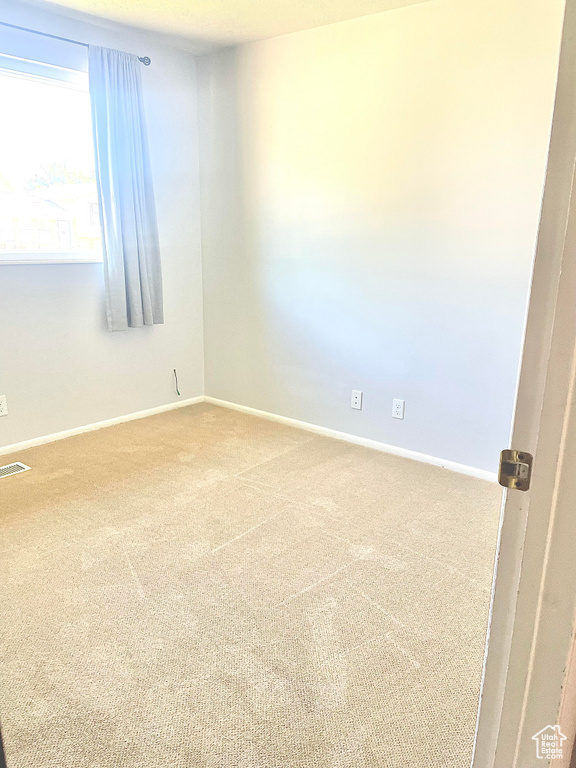 Empty room with carpet, visible vents, and baseboards