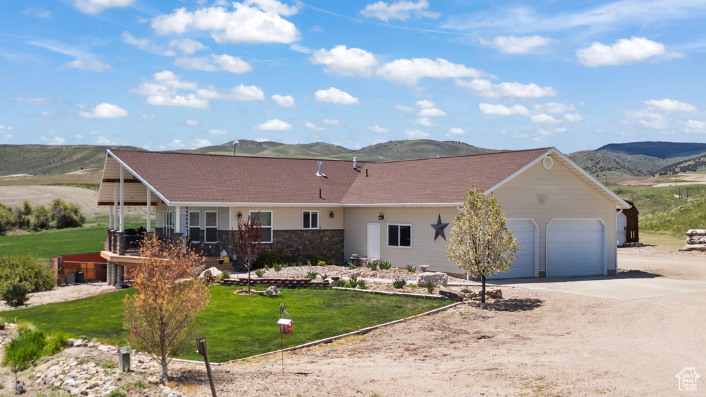 View of front of house with concrete driveway, a mountain view, a garage, and a front yard