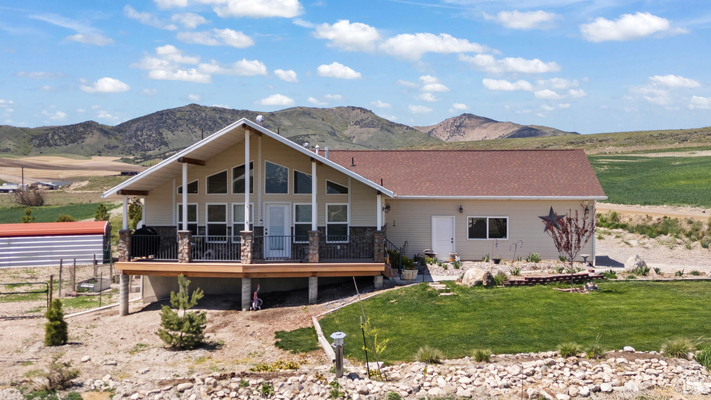 Rear view of house with a deck with mountain view and a lawn
