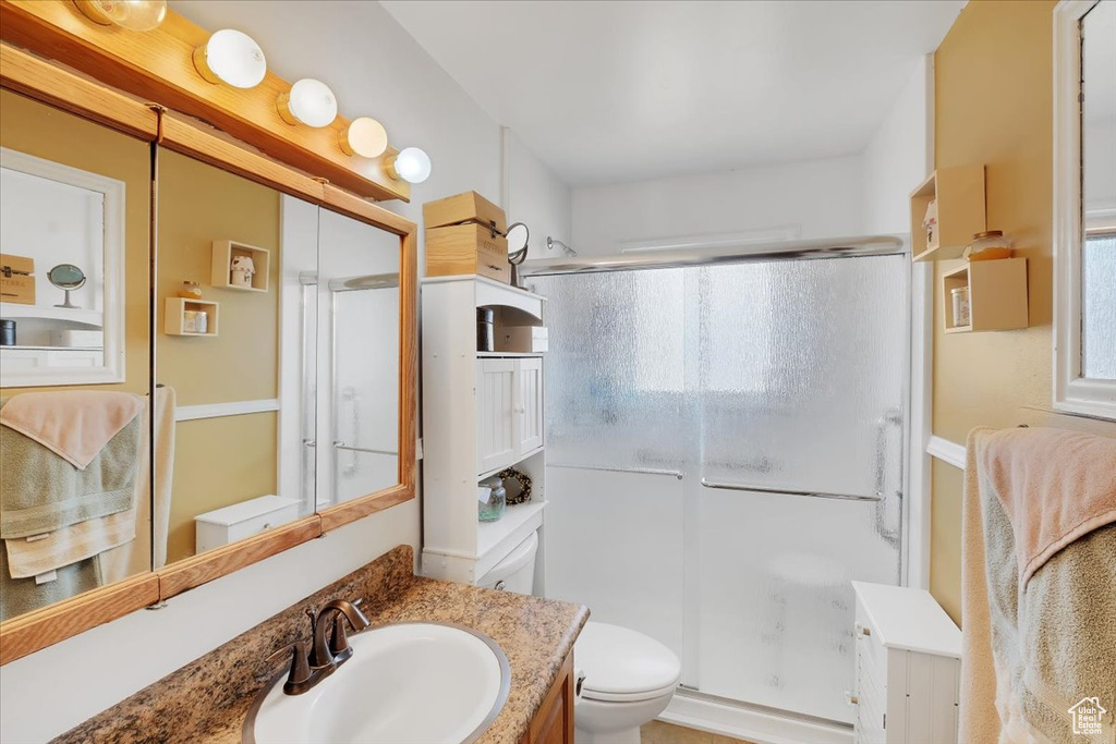 Bathroom with vanity, toilet, and a stall shower