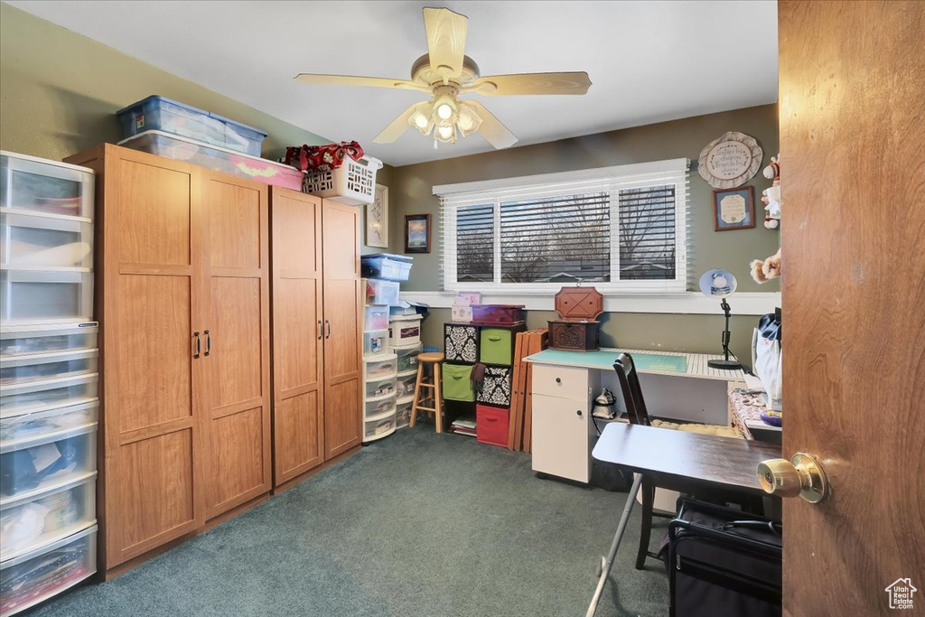 Office area with a ceiling fan and dark carpet
