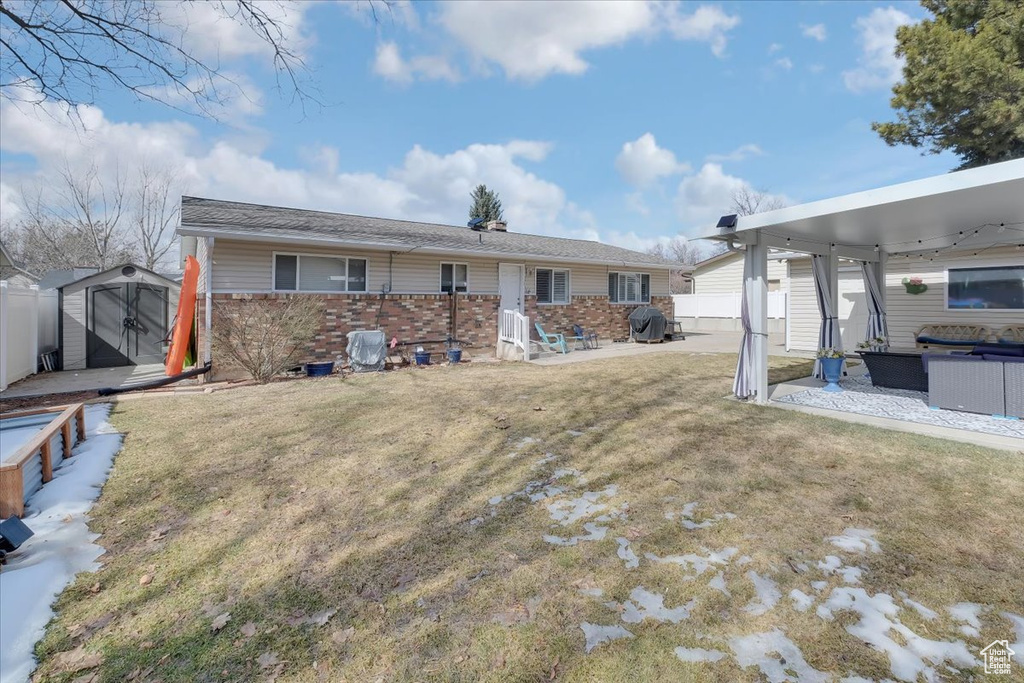 Rear view of property featuring brick siding, a storage shed, an outdoor structure, and fence