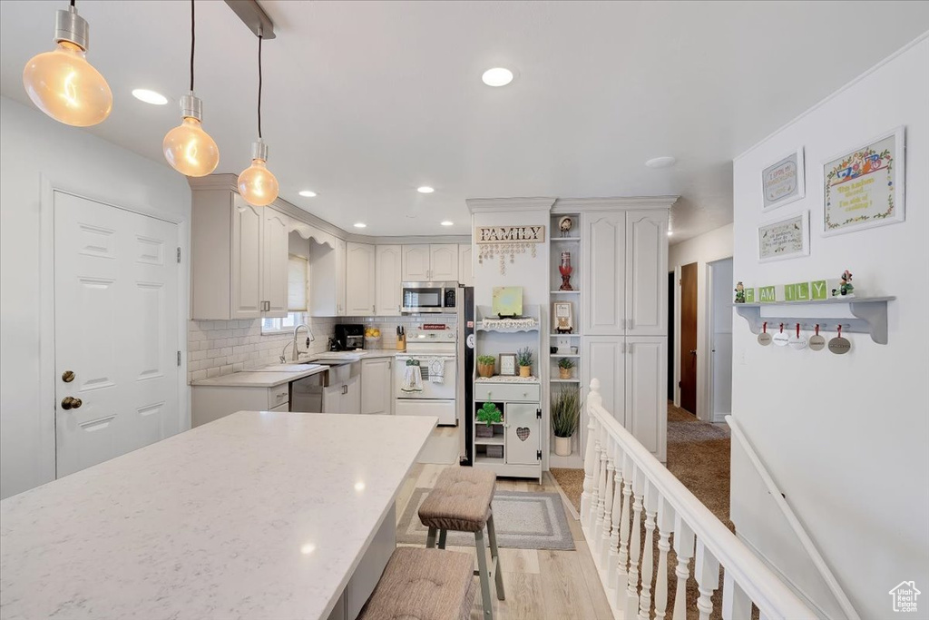 Kitchen featuring a breakfast bar, open shelves, stainless steel microwave, white electric range, and tasteful backsplash